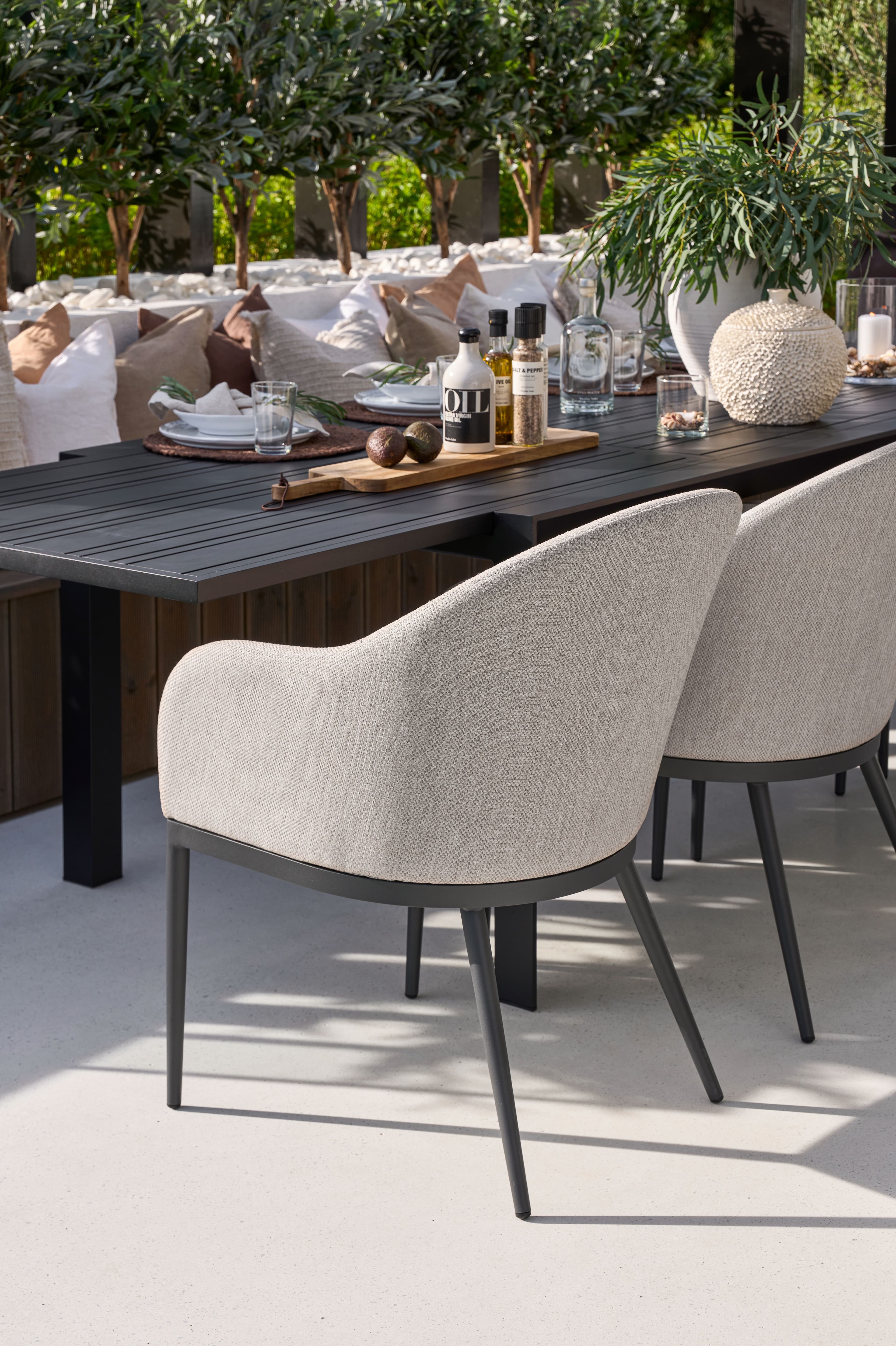 Umra stol i naturmateriale og Umra sidebord i tre, dekorert med puter, en vase og en plante